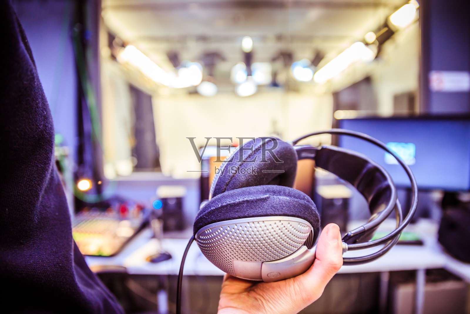 錄音室錄音:一個戴著耳機的年輕人正坐在錄音室里,錄音室的背景模糊不清